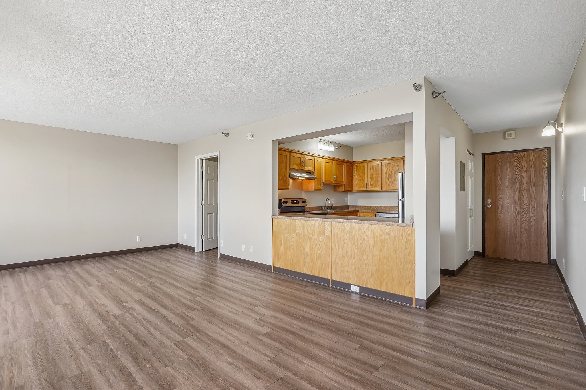 Irvine Park Towers apartment living area with open kitchen, breakfast bar and wood-look flooring